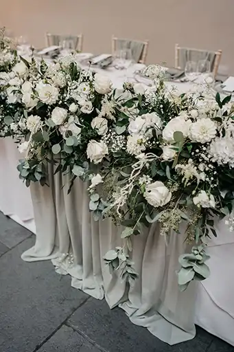 Lush top table floral garland featuring roses, lisianthus, and greenery at a Cotswolds wedding.