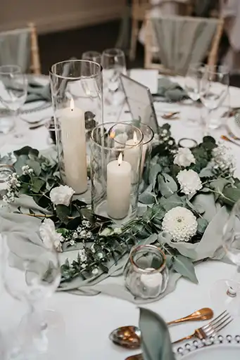 Table decor with candles, greenery, and white blooms at a Cotswolds wedding reception.