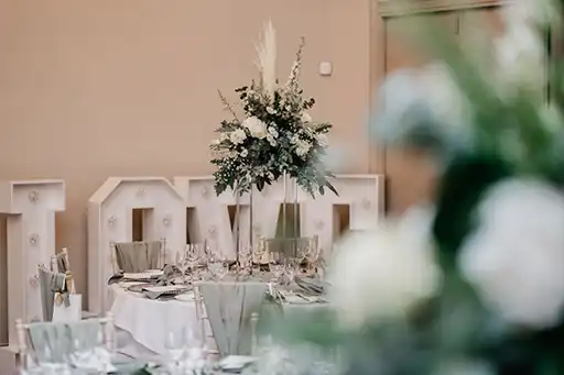 Elegant tall floral centrepiece with white roses and greenery by a wedding florist in the Cotswolds at Blackwell Grange.