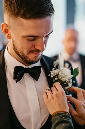 Groom getting his white rose boutonniere adjusted before the ceremony.