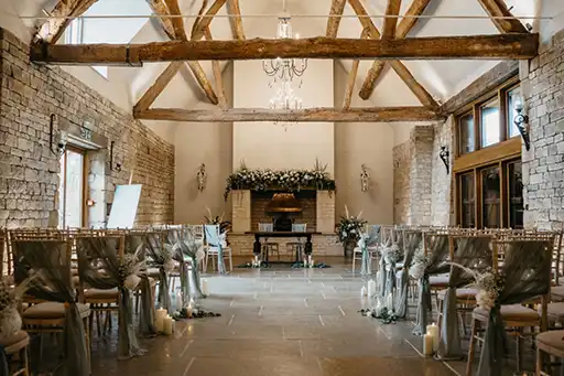 Thatch Barn ceremony setup at Blackwell Grange with greenery and floral accents by a wedding florist in the Cotswolds.