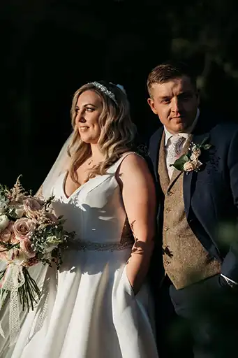 Bride and groom posing outdoors in soft evening light with lush bouquets at The Mill Barns.