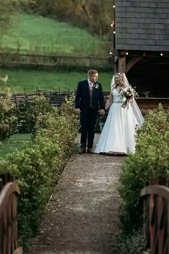 Bride and groom walking along a garden pathway at The Mill Barns.