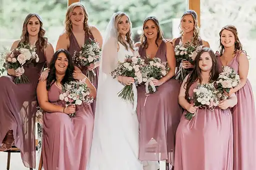 Bridal party group photo with bridesmaids in mauve dresses and groomsmen in navy suits at The Mill Barns