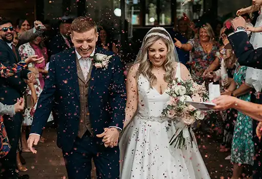 Bride and groom walking through confetti at their spring wedding at The Mill Barns.