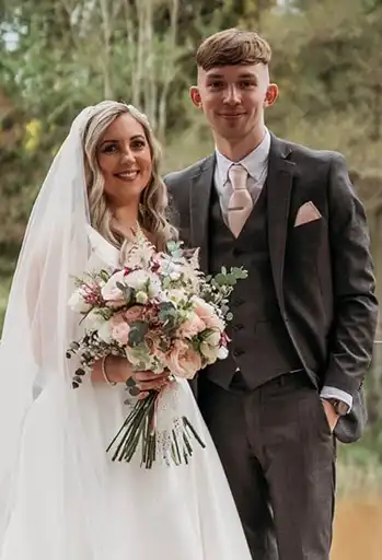 Bride and groomsman smiling and posing with a blush and ivory bouquet at The Mill Barns.